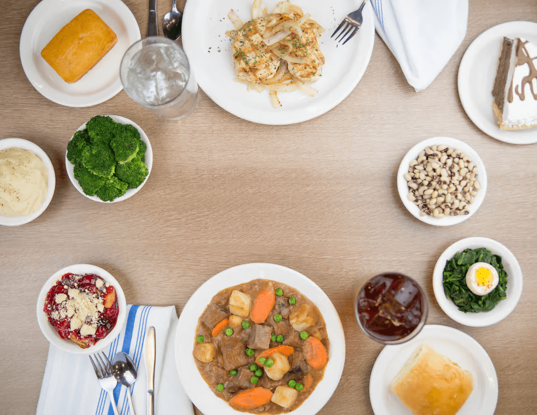 Overhead view of a spread of dishes including salads, stews, and sides on a wooden table