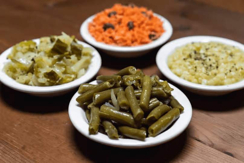 Three bowls of Southern-style vegetable sides including green beans, carrots, and coleslaw